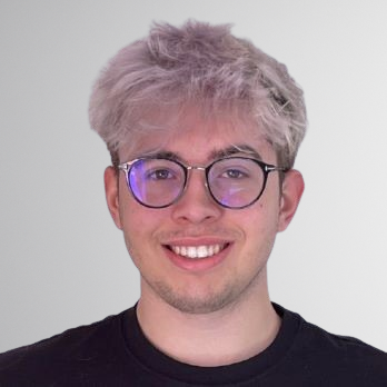 Porträt eines jungen Mannes mit heller Frisur und runder Brille vor neutralem Hintergrund