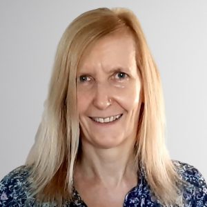 Porträt einer lächelnden Frau mit langen blonden Haaren vor hellem Hintergrund