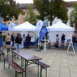 Besucherinnen und Besucher an Informationsständen mit Pavillons und Sitzgarnituren beim Klimaschutztag auf dem Berliner Platz.